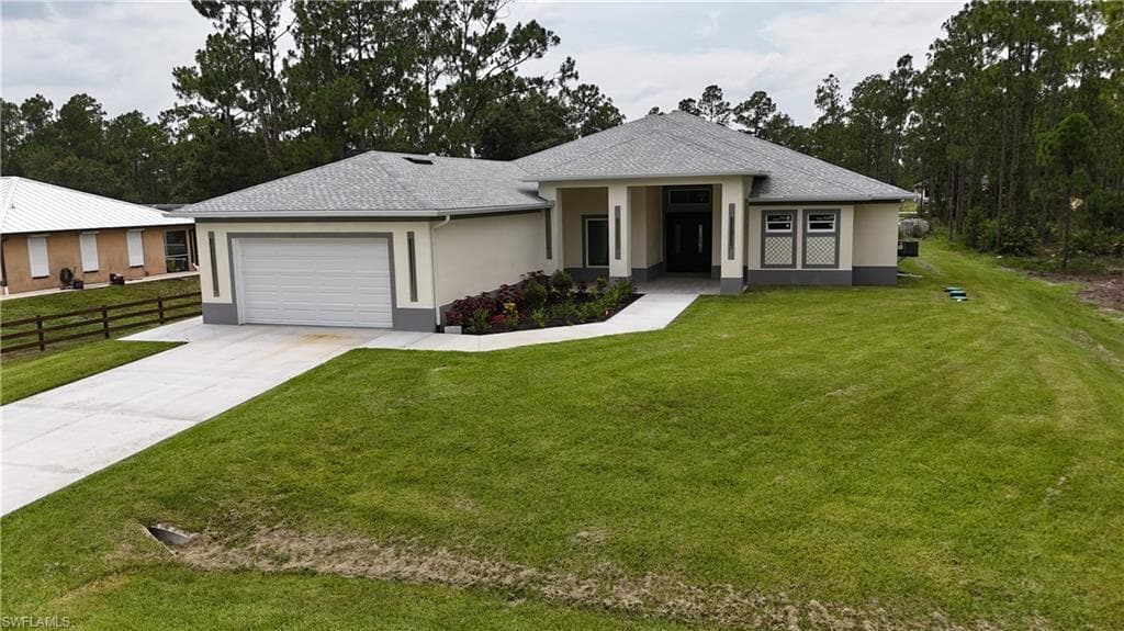 Contemporary exterior with a covered entry, two-car garage, manicured lawn, and planted garden beds