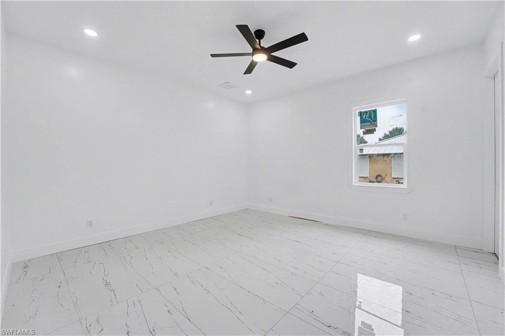 Spacious room featuring large format white tile flooring with grey veining, recessed lighting, and a modern black ceiling fan