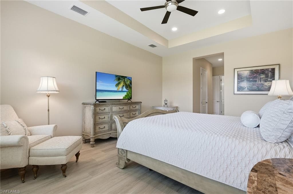 Recessed lighting and a ceiling fan illuminate the primary bedroom, featuring Karastan luxury flooring and a tray ceiling.