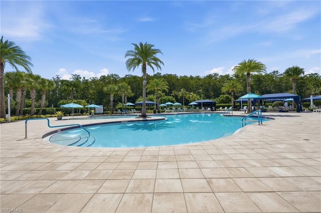 Resort-style swimming pool featuring a curved design with cabanas for shaded areas.