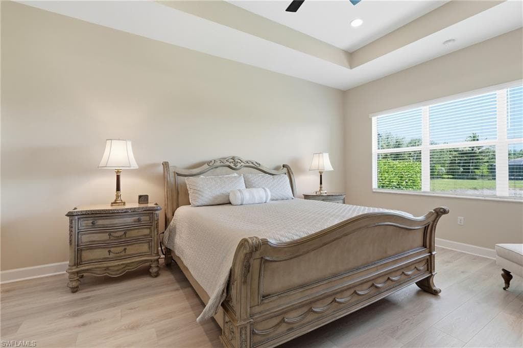 Primary bedroom has Karastan luxury flooring, a tray ceiling with recessed lighting and a large window providing natural light.