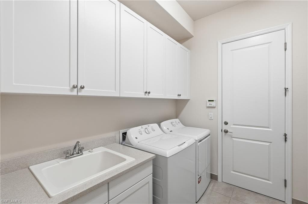 Laundry room featuring white shaker cabinetry, an integrated utility sink, a light-toned countertop, and light-colored floor tiling
