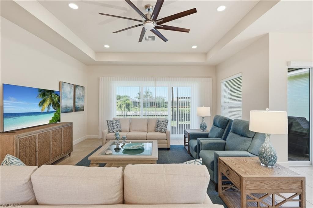 Living area featuring a tray ceiling with recessed lighting and a ceiling fan