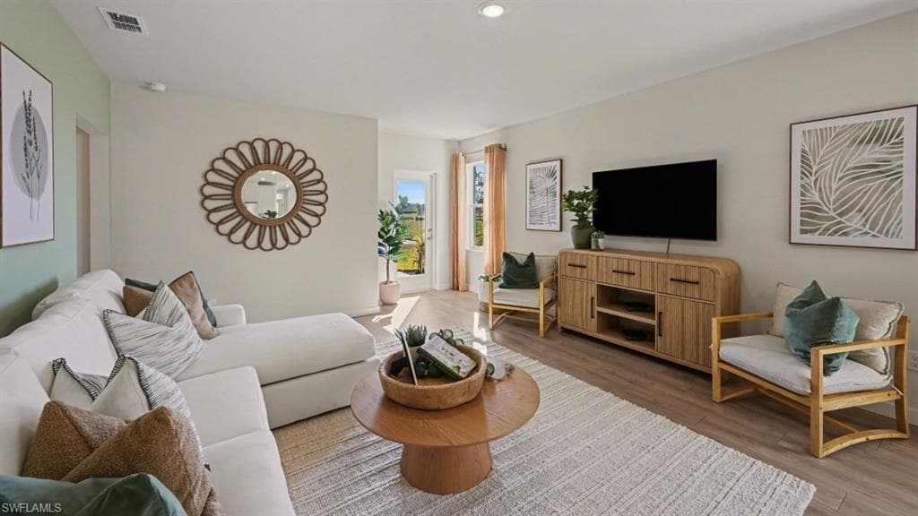 Spacious living area featuring light wood-finish flooring and recessed lighting