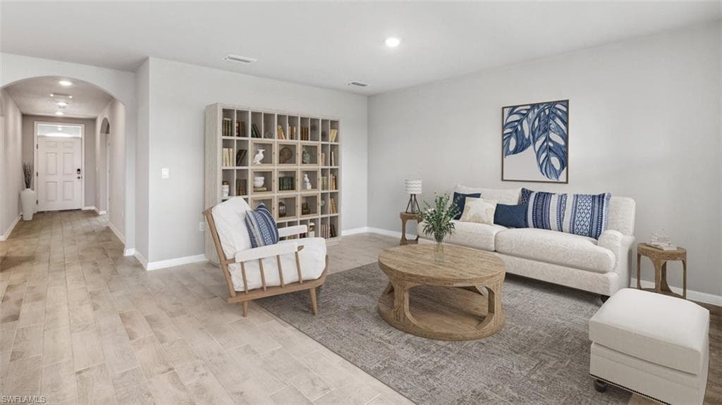Virtually staged - Spacious living area featuring wood-finish flooring, light gray wall tones, and recessed lighting