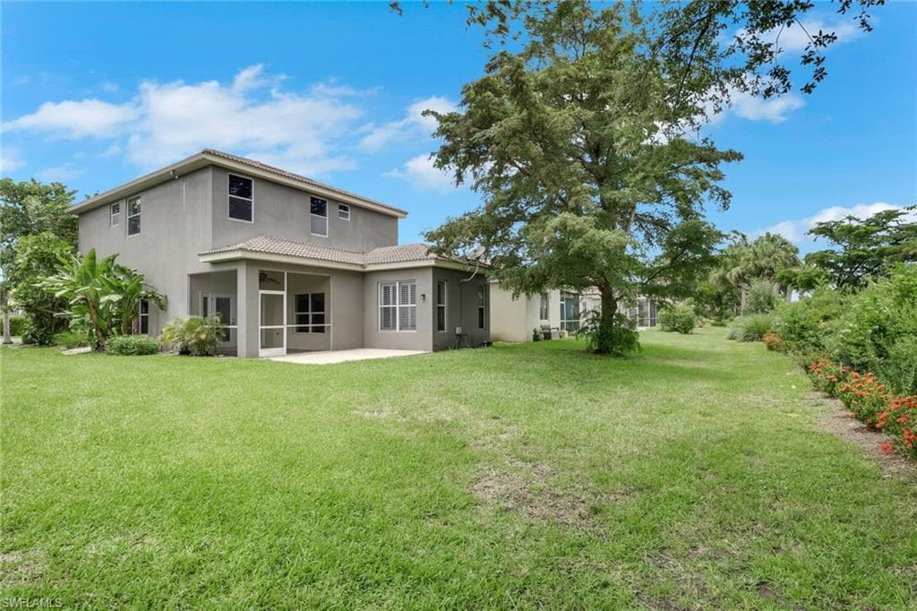 Spacious backyard with a large lawn area, mature trees, a screened patio, and an open patio space
