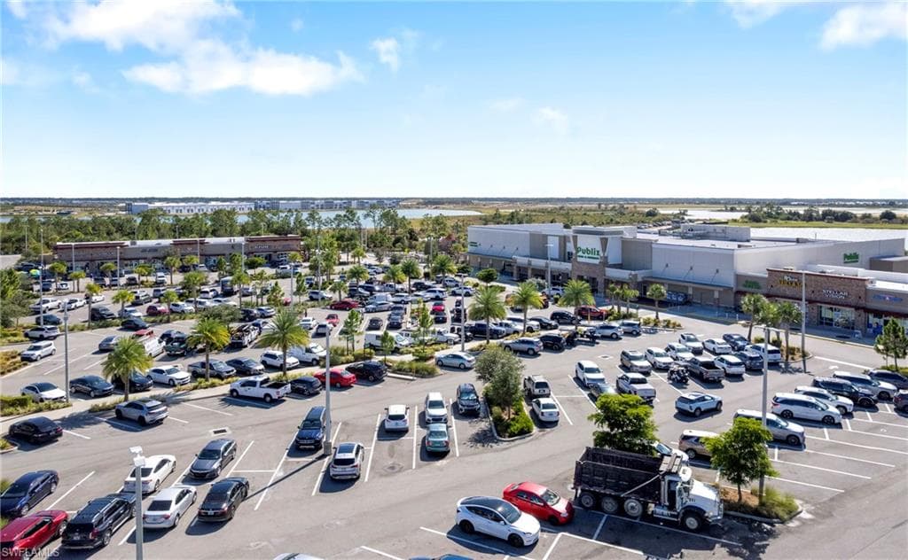 Expansive retail complex featuring multiple storefronts, a large paved parking area, and mature palm tree landscaping