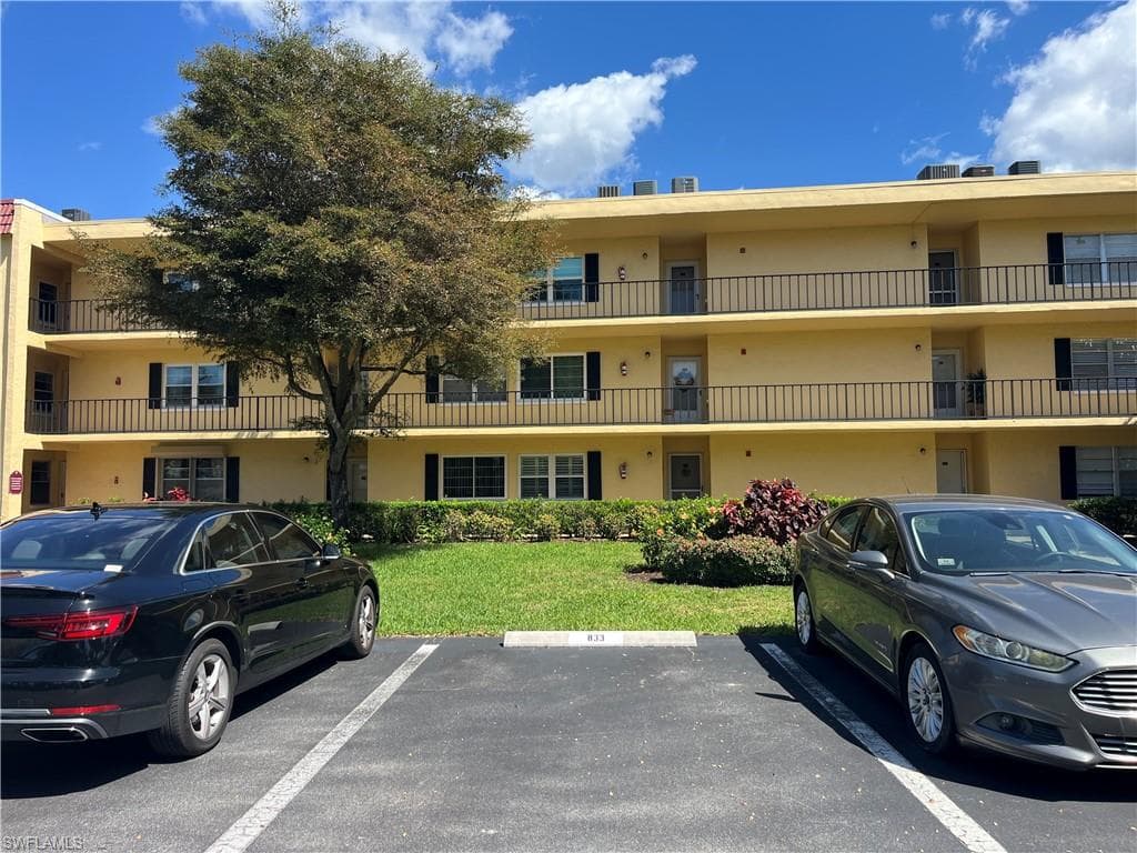 View of apartment building / complex featuring uncovered parking
