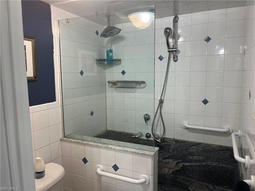 Bathroom with tiled shower and tile walls