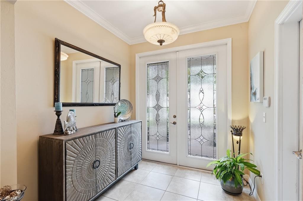 Entryway featuring double doors with decorative frosted glass inserts, crown molding, and tiled flooring