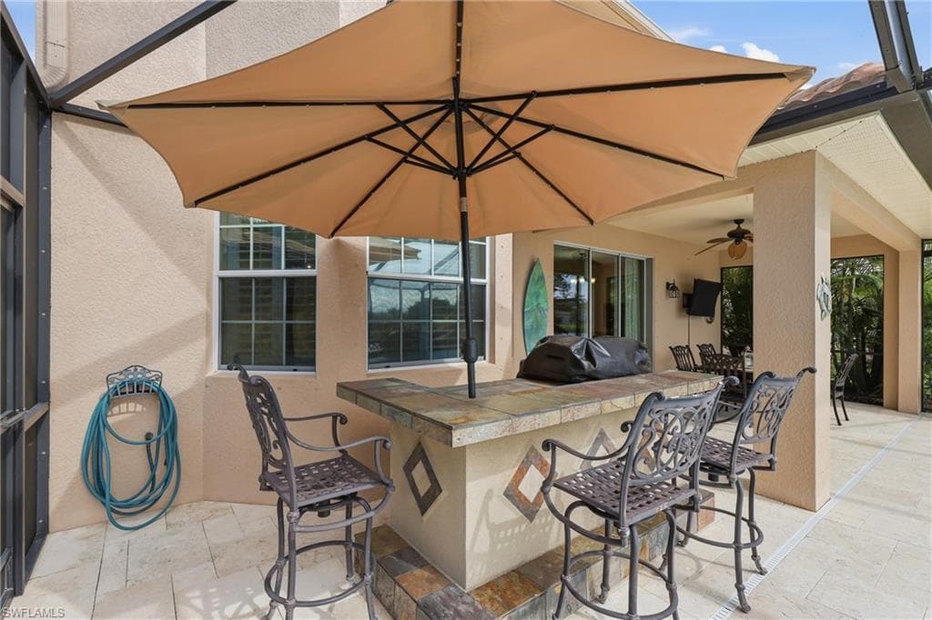 Outdoor bar area featuring a tiled countertop, integrated grill, and a patio umbrella