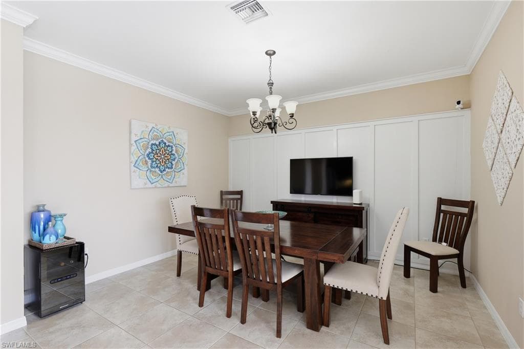 Light-toned tile flooring, crown molding, and wainscoting details characterize this room
