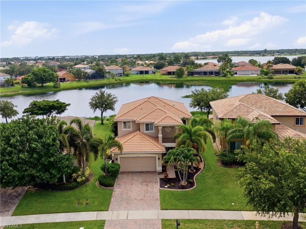 Two-story residence featuring a tile roof, an attached garage, and a paver driveway