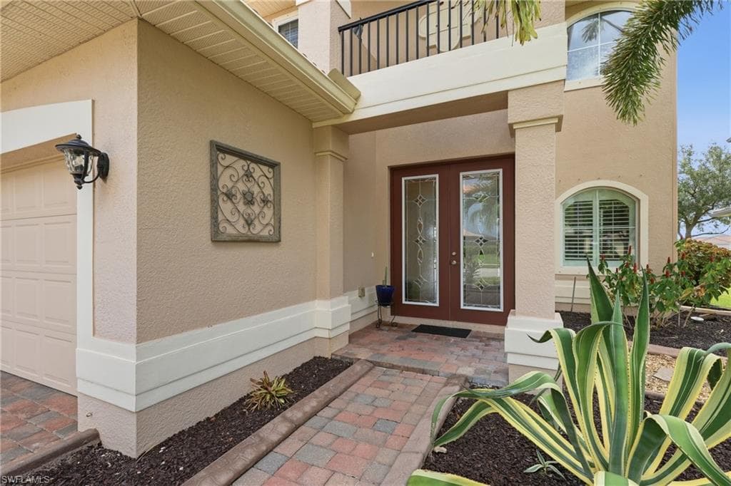 Stucco exterior with a paver walkway leading to a double-door entry