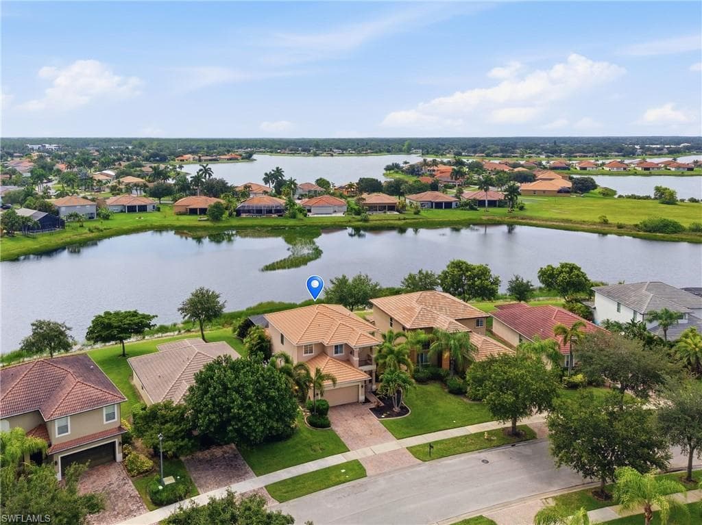Two-story stucco residence with a tile roof, an attached two-car garage, and a paver driveway