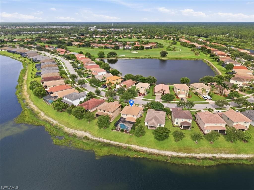 Aerial perspective of a residential community featuring a prominent central lake and surrounding golf course