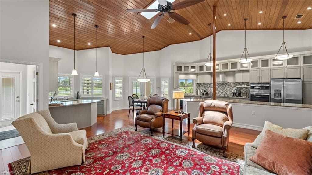 Spacious living area featuring a vaulted wood-finish ceiling with a skylight, recessed lighting, and a ceiling fan