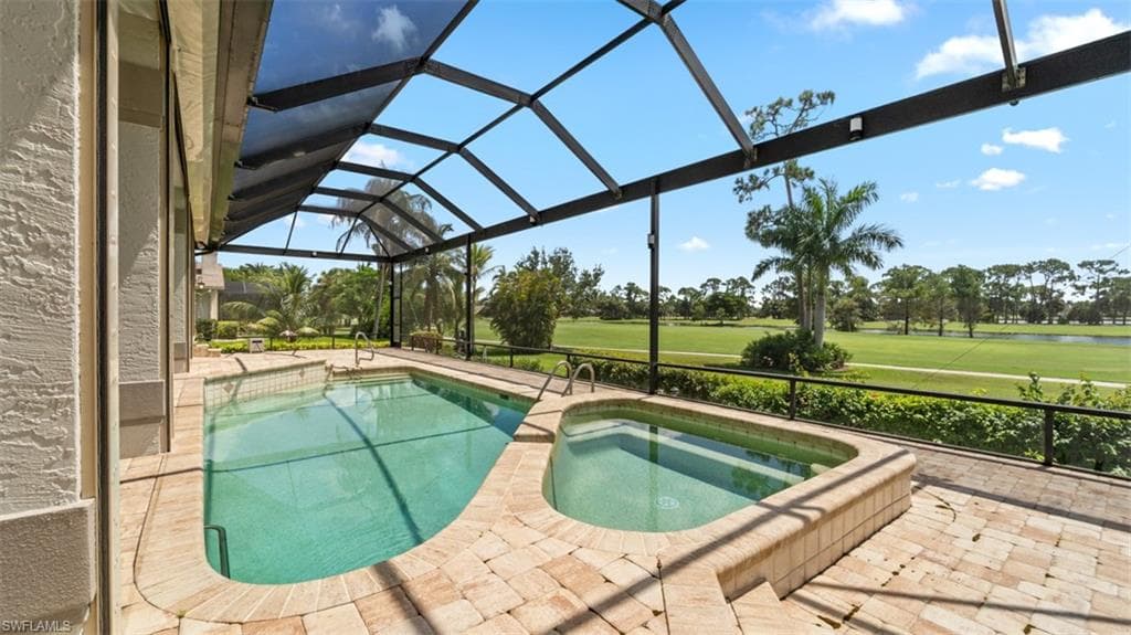 Expansive views of golf course & water. Screened lanai featuring a swimming pool and attached spa, surrounded by stone paver decking