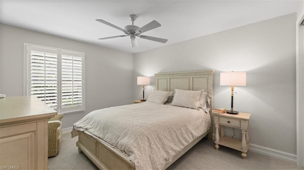 Bedroom featuring plantation shutters, neutral wall color, ceiling fan, carpet flooring, and a built-in closet with white trim