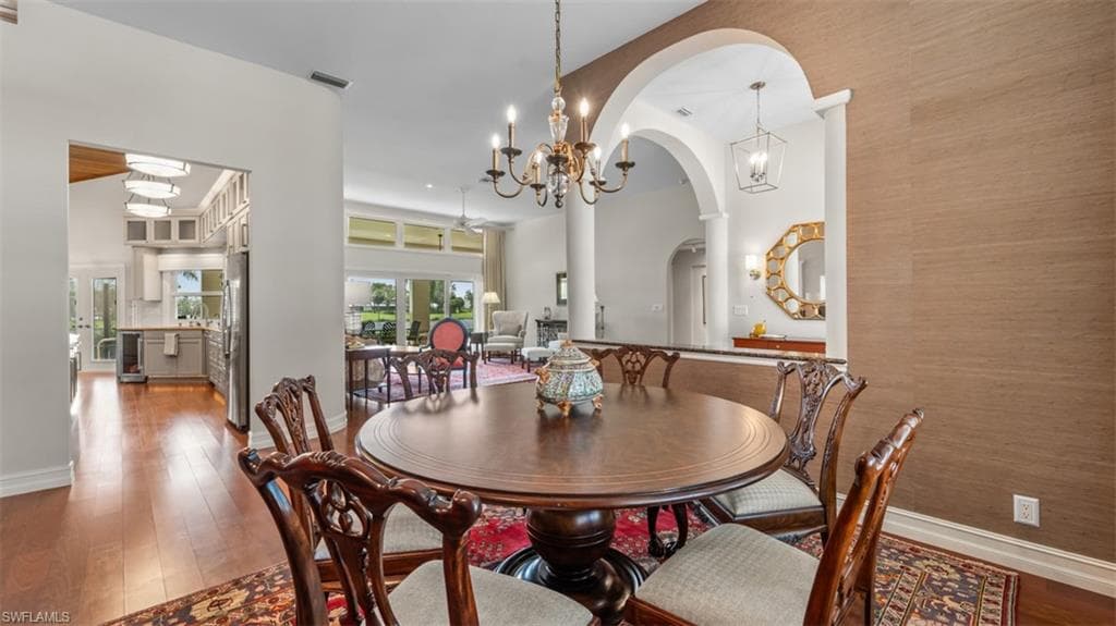Formal dining area featuring rich wood-finish flooring, a decorative chandelier, and an arched entryway