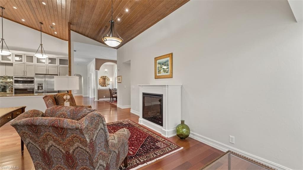 Living area featuring a vaulted wood-paneled ceiling, a built-in fireplace with a white mantel, and wood-finish flooring