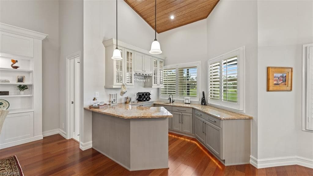 Built-in Serving Bar, featuring stone countertops, integrated sink, and upper cabinetry with glass inserts