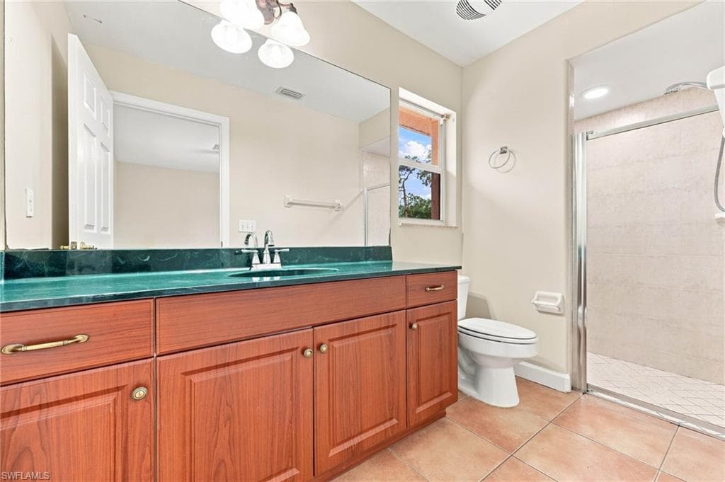 Spa-inspired primary bathroom showcasing warm wood cabinetry with ample storage, a striking turquoise countertop, dual sink configuration, and a spacious walk-in shower with tile surround and frameless glass enclosure