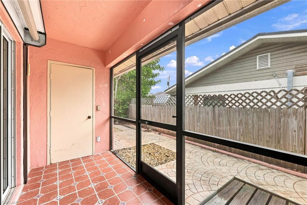 Screened patio featuring terracotta-toned tile flooring with geometric patterns, textured coral-colored walls, and a white exterior door