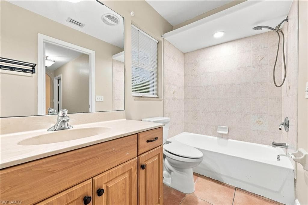 Full bathroom featuring a wood-finish vanity with an integrated sink, a large mirror, and a tiled shower/tub combination with a handheld showerhead