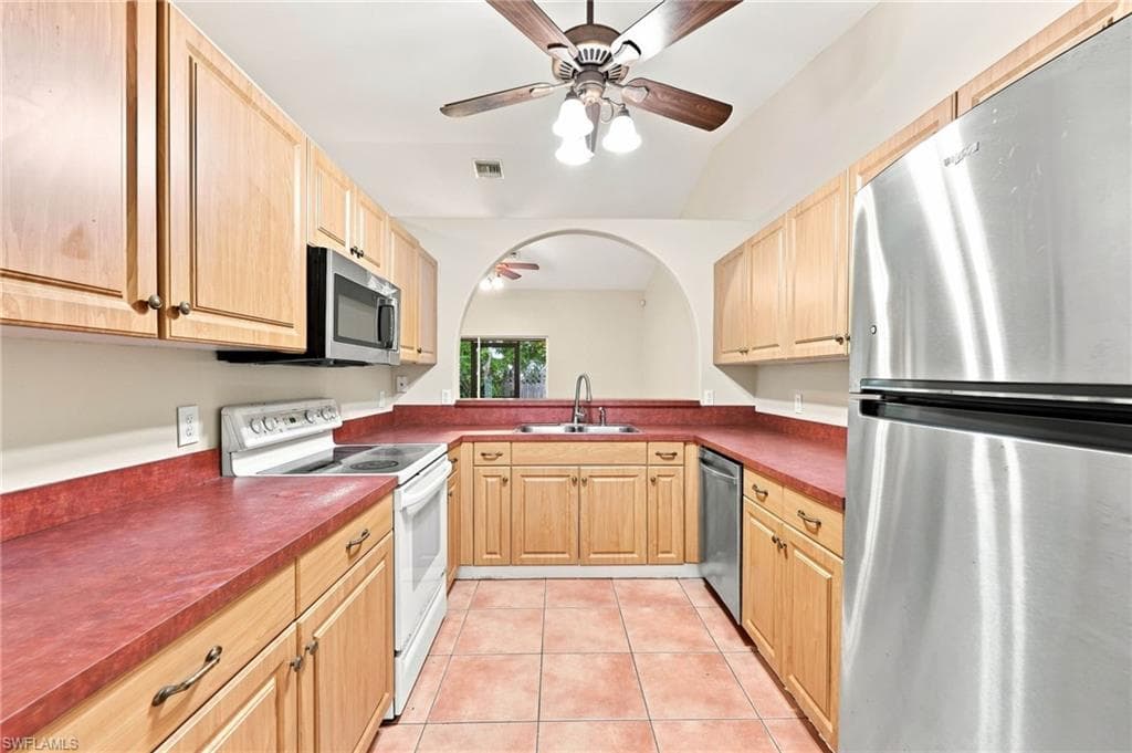Kitchen featuring wood cabinetry, red countertops, tile flooring, and vaulted ceiling