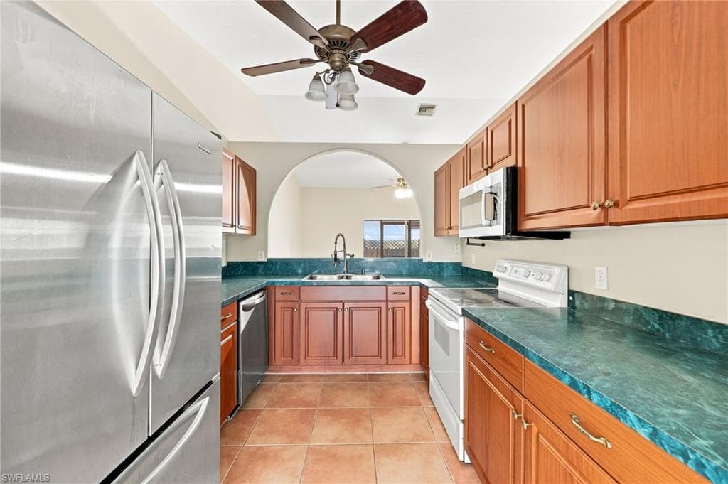 Galley kitchen featuring warm wood cabinetry, teal tile backsplash, and matching teal countertops
