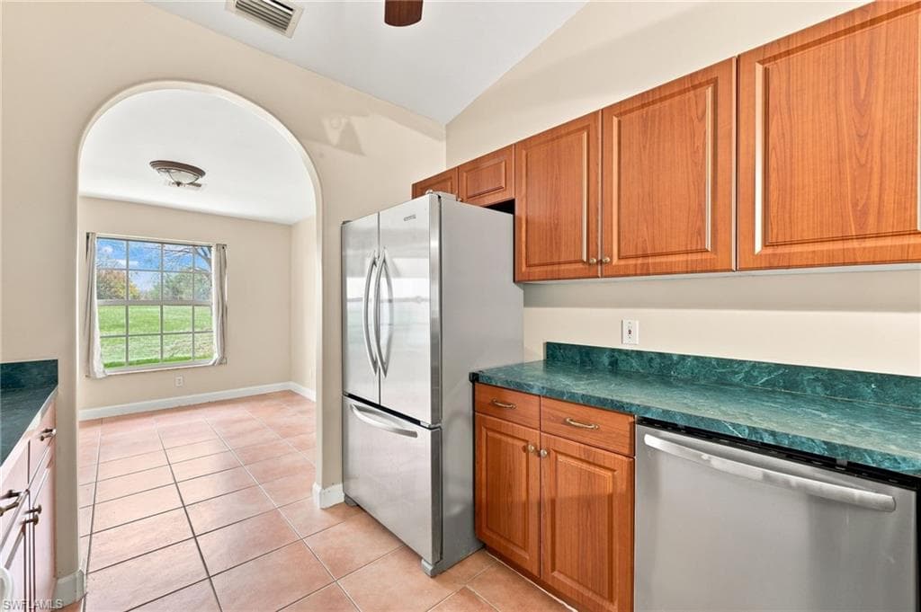 Kitchen featuring wood-finish cabinetry, green marble-look countertops, and stainless steel appliances including a refrigerator and dishwasher