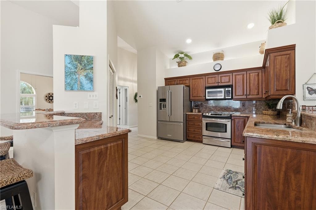 Kitchen featuring wood cabinetry with ample storage, stainless steel appliances, and a double-basin sink