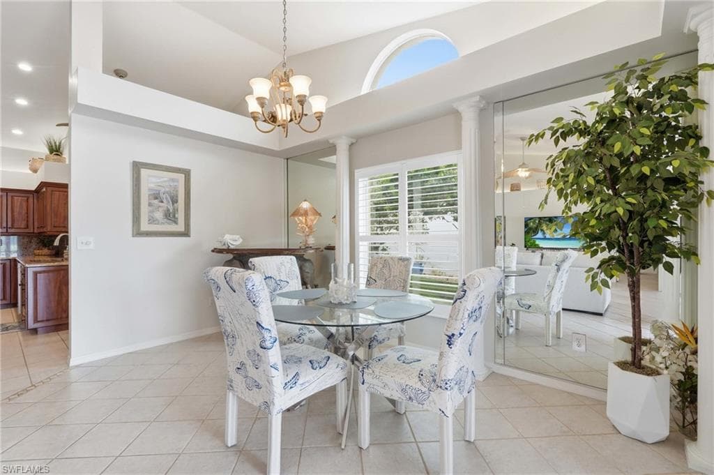 Dining area featuring tile flooring, a decorative chandelier, and a large window with white plantation shutters