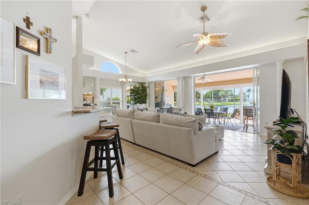 Open-concept living area with tile flooring and decorative inlay, featuring a breakfast bar with stone countertop