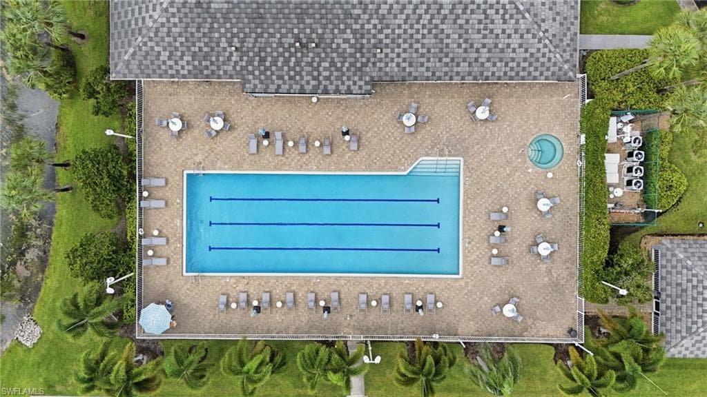 Outdoor recreational area featuring a large swimming pool with lane lines, a circular spa, and an extensive paver deck