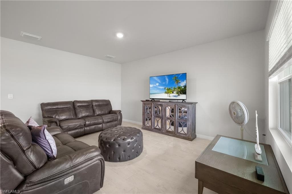 Carpeted entertainment area featuring light gray walls, recessed lighting, and a window with horizontal blinds
