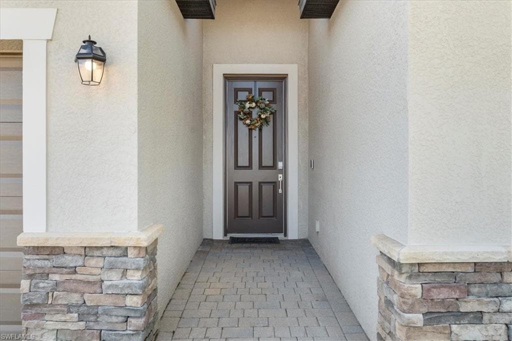 Entryway featuring a paneled front door with decorative trim and a wrought iron lantern sconce