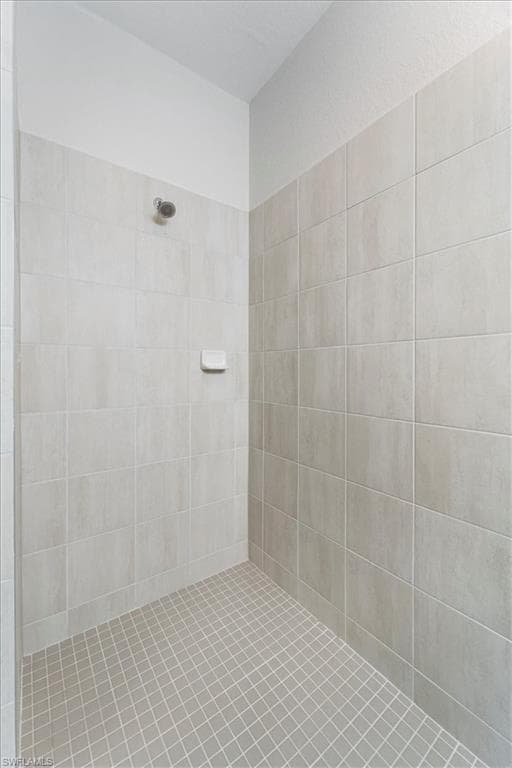 Tiled shower stall featuring a chrome shower head and a built-in soap dish