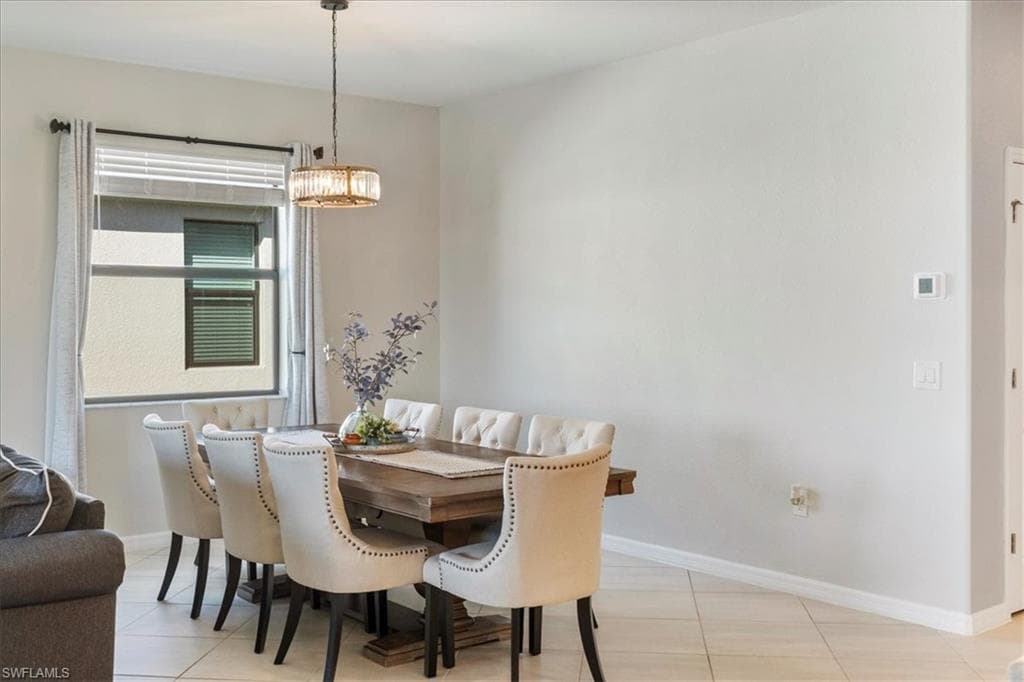 Dining area featuring a contemporary chandelier, large window with blinds, and light-toned tile flooring