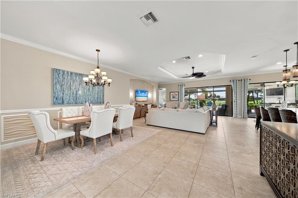 Open-concept living area featuring large format tile flooring, a tray ceiling with recessed lighting and a ceiling fan, and sliding glass doors to the exterior