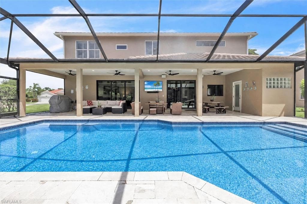 Expansive pool area featuring a screened enclosure, a large swimming pool with integrated steps, an extended covered patio, and multiple large sliding glass doors