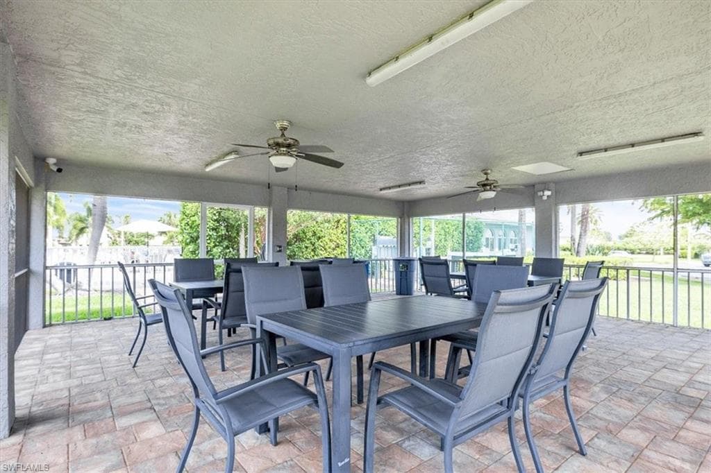 Screened patio area featuring a textured ceiling with two ceiling fans, recessed lighting, and brick-patterned pavers