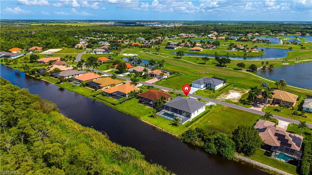 Aerial overview showcasing a property with a screen-enclosed pool, situated alongside a waterway