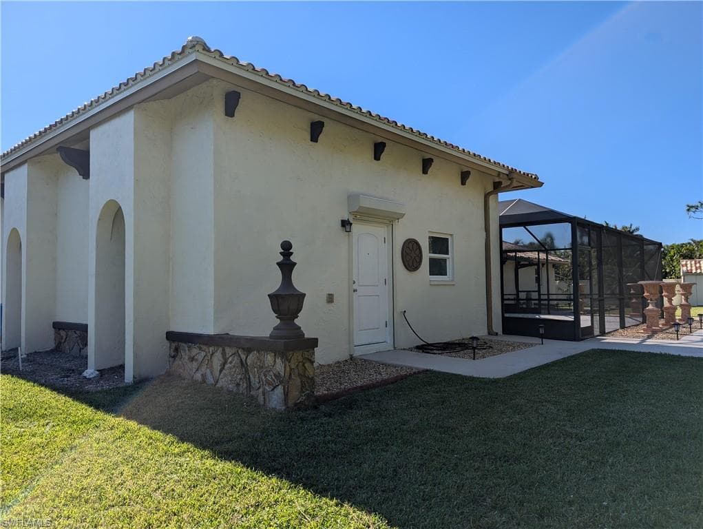 Back of property featuring a lawn, glass enclosure, and a patio area