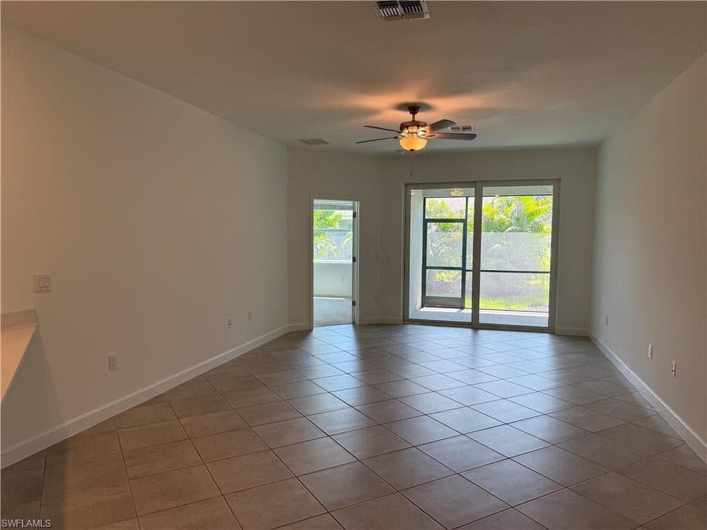 Spacious open-concept room featuring neutral tile flooring and a ceiling fan with integrated lighting