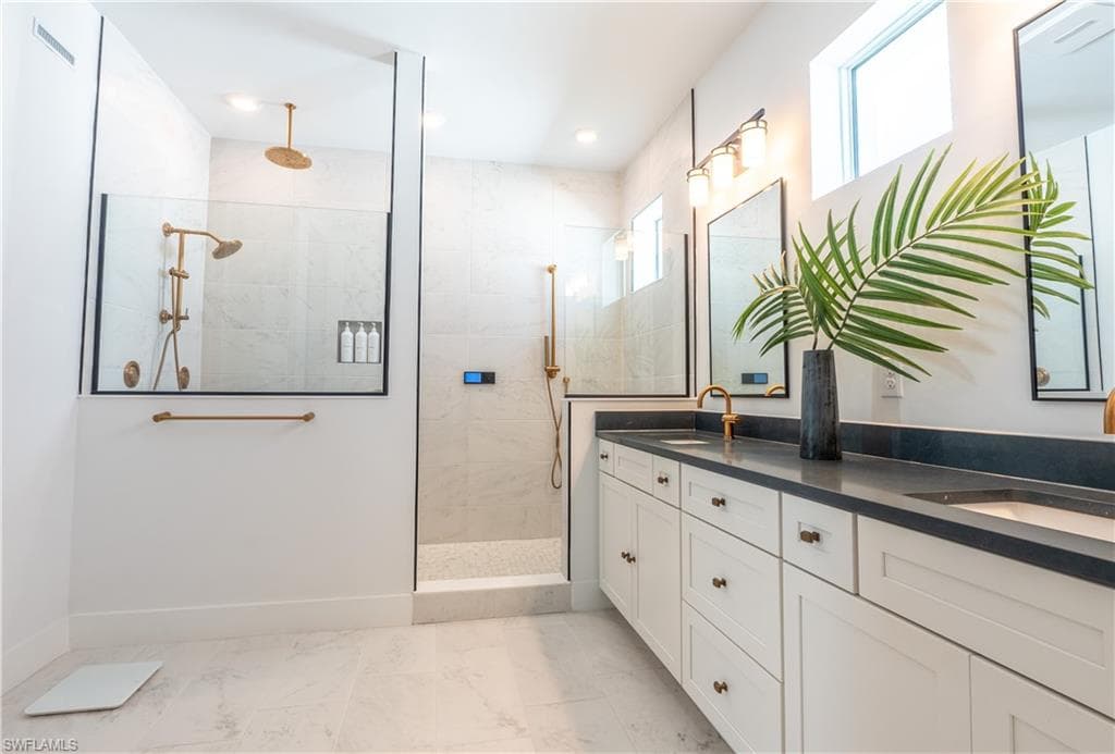 Spacious bathroom featuring a dual vanity with dark countertops and white cabinetry