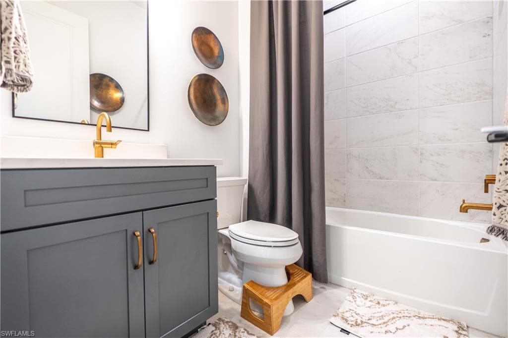 First floor FULL Bathroom featuring a gray vanity with gold-tone hardware, a white countertop, and a matching gold-tone faucet