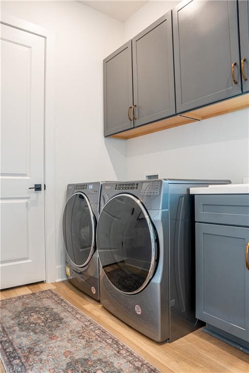 Utility room featuring laundry sink, wood-finish flooring, white walls, and built-in gray cabinetry with gold-tone hardware