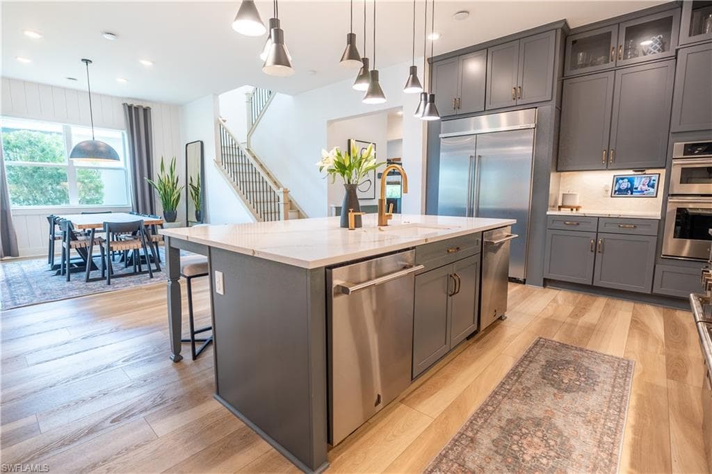 Central kitchen island with a light-toned countertop, complete with stainless steel appliances and pendant lighting